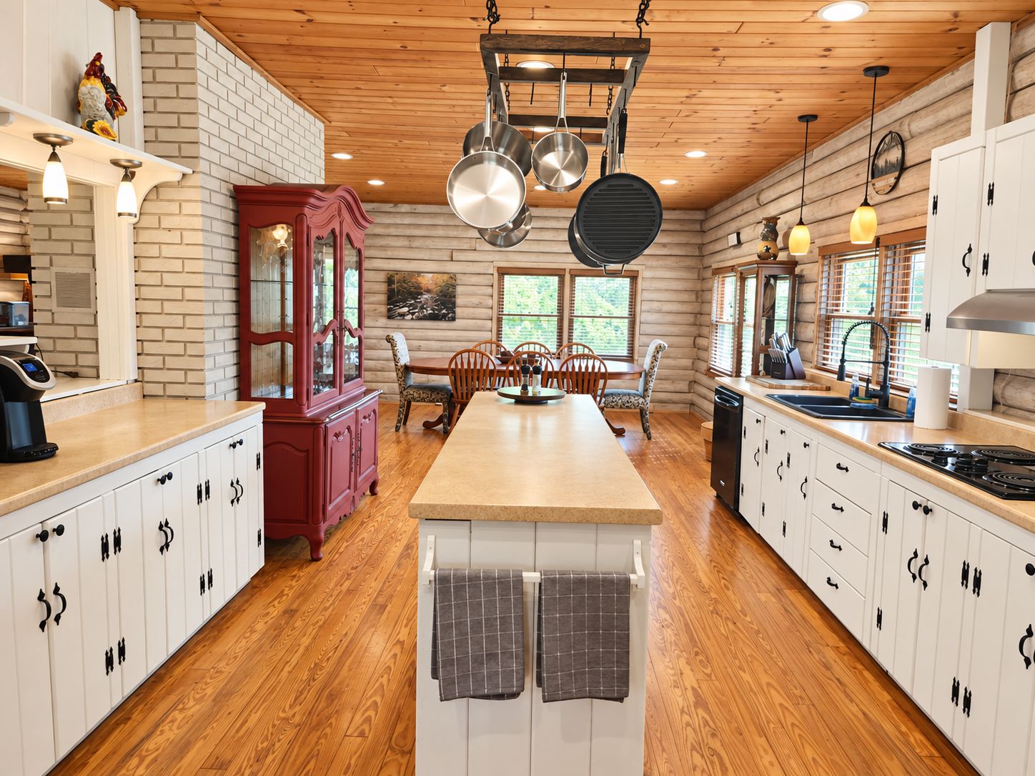 A kitchen with a central island, wooden cabinets, and hanging pots.