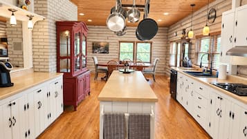 A kitchen with a central island, wooden cabinets, and hanging pots.