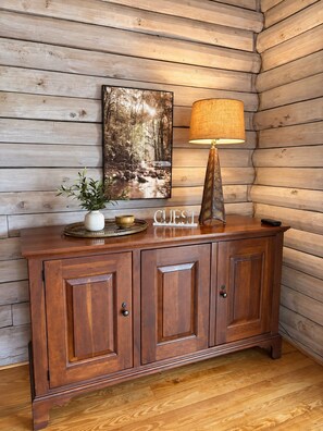 Ein Holzkabinet mit einer Lampe, einem gerahmten Bild und einer Schale mit einer Pflanze und Schalen.