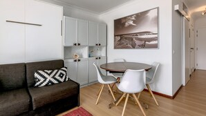Un espacio habitable compacto con sofá, mesa de comedor, sillas y zona de cocina.