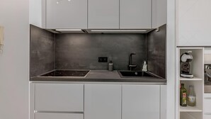 Una cocina moderna con estufa integrada, pileta y luces en el techo.