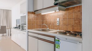 Una cocina moderna con armarios blancos, un lavamanos de acero inoxidable y un horno empotrado.