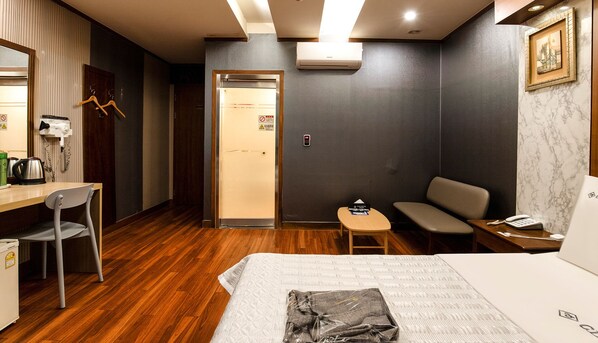A hotel room with a bed, a desk with a chair, a small table, a sofa, and a wardrobe. - CLIO MOTEL (Incheon)