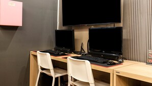 A workspace with two computer desks, each with a monitor, keyboard, and mouse. There are two white chairs, and a pink storage box is visible on the wall. - CLIO MOTEL (Incheon)