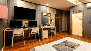 A hotel room with a wooden desk, two computer monitors, a small refrigerator, and a bed with a white comforter. - CLIO MOTEL (Incheon)