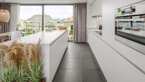 A modern kitchen with a large island, a view to the outside, and a built-in appliance shelf.