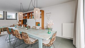A dining area with a light blue table, wicker chairs, and hanging rattan lights.