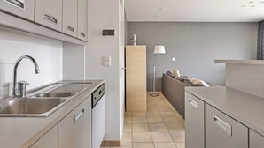 A modern kitchen with stainless steel appliances, a built-in dishwasher, and a grey countertop.