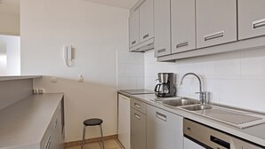 A compact kitchen with a dishwasher, a coffee maker, and a sink.