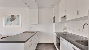 Eine moderne Küche mit weißen Schränken, einer schwarzen Arbeitsplatte und einer gefliesten Spritzschutzwand.