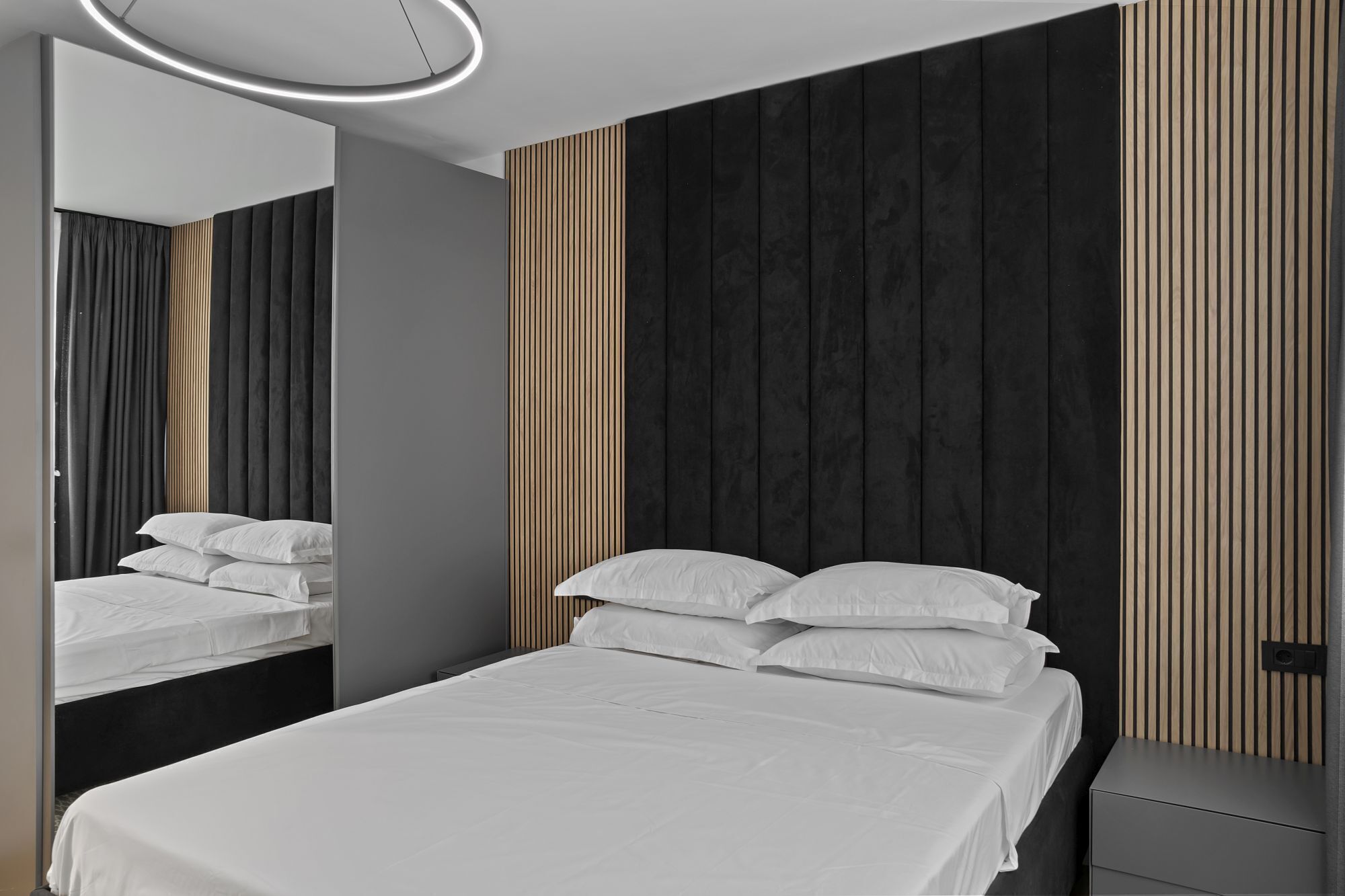 Un dormitorio moderno con una cama, una mesita de noche y un espejo.