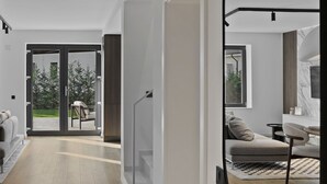 A spacious living area with a wooden floor, a sofa, a dining table, and a large mirror. - New Villa next to the forest and Therme SPA (Corbeanca)