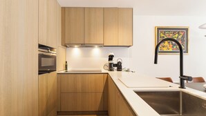 Una cocina moderna con armarios de madera, un lavamanos de acero inoxidable y una cafetera.