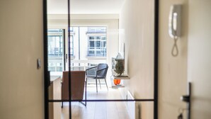 Vista interior de una habitación de hotel con balcón, una silla, una mesa y un florero.