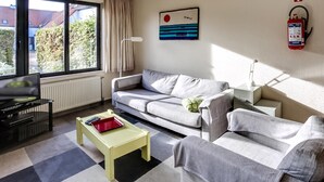 Una sala de estar con un sofá, una mesa de centro, un televisor y un extintor de incendios en la pared.