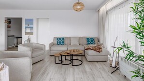A modern living room with a sofa, two coffee tables, and a hanging light fixture. - 2 bedroom accommodation in De Panne (De Panne)