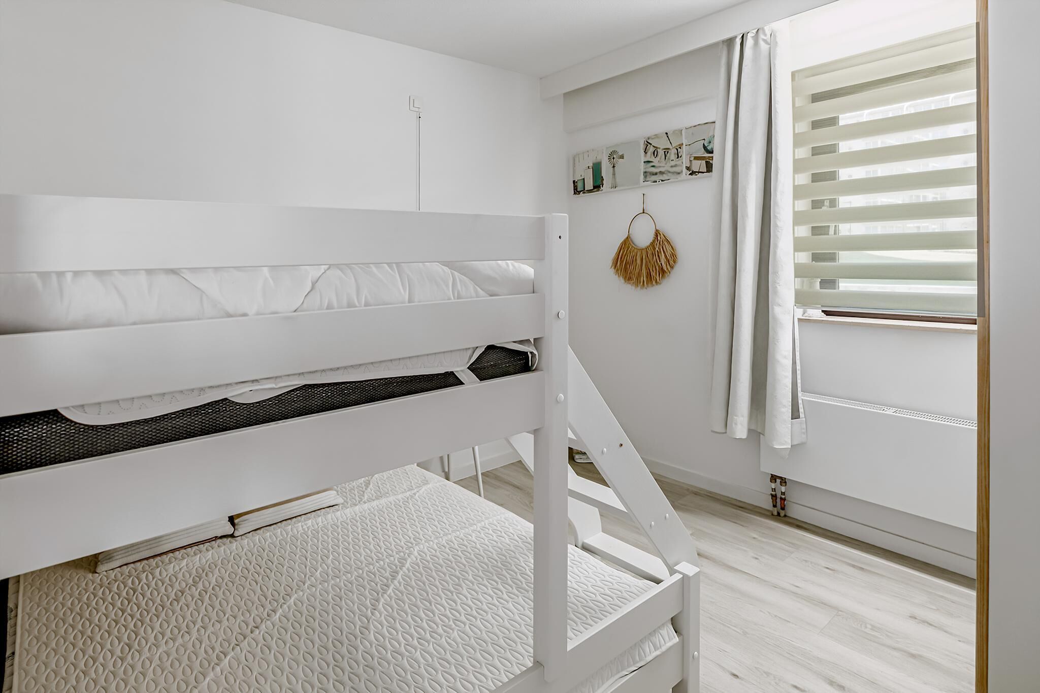 Una cama litera blanca con un colchón y una litera inferior con una almohada.