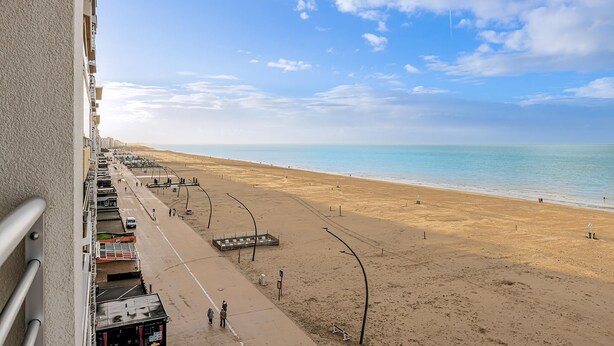 A beach with a clear sky, a sandy shore, and a few people walking. - 2 bedroom accommodation in De Panne (De Panne)