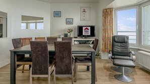 A modern living room with a dining area, a TV, and a view of the sea. - 2 bedroom accommodation in De Panne (De Panne)