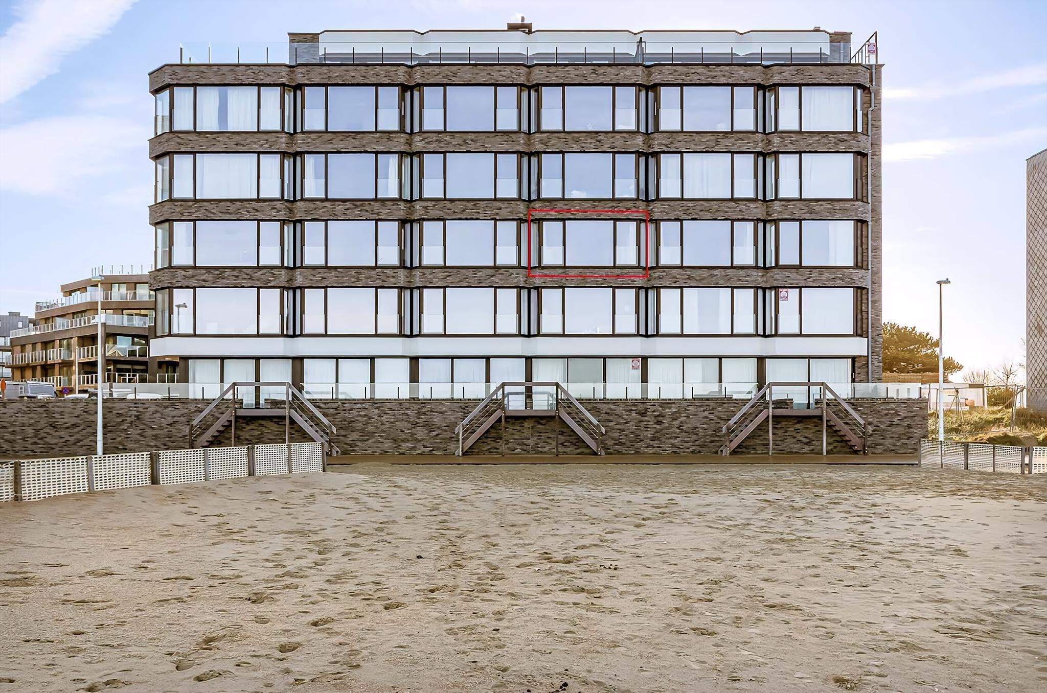 A multi-story building with a modern architectural design, featuring a series of windows and a central staircase.