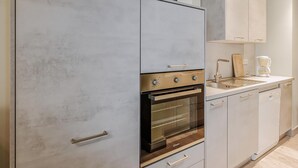 Une cuisine moderne équipée d’un four encastré, d’un évier et d’une machine à café.
