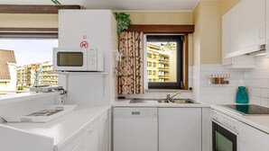 A modern kitchen with white cabinetry, a microwave, a dishwasher, a sink, and an oven. - 2 bedroom accommodation in Sint Idesbald (Sint Idesbald)