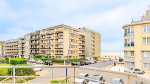A multi-story residential building with balconies, a parking area with cars, and a clear view of the beach in the background. - 2 bedroom accommodation in Sint Idesbald (Sint Idesbald)