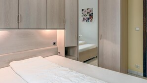A bedroom with a bed, wooden wardrobe, and a small bedside table. - 2 bedroom accommodation in Sint Idesbald (Sint Idesbald)