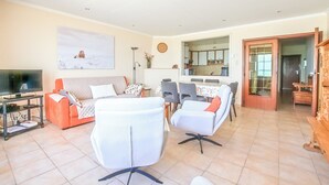 A living room with a sofa, chairs, a TV, and a dining area with a table and chairs.