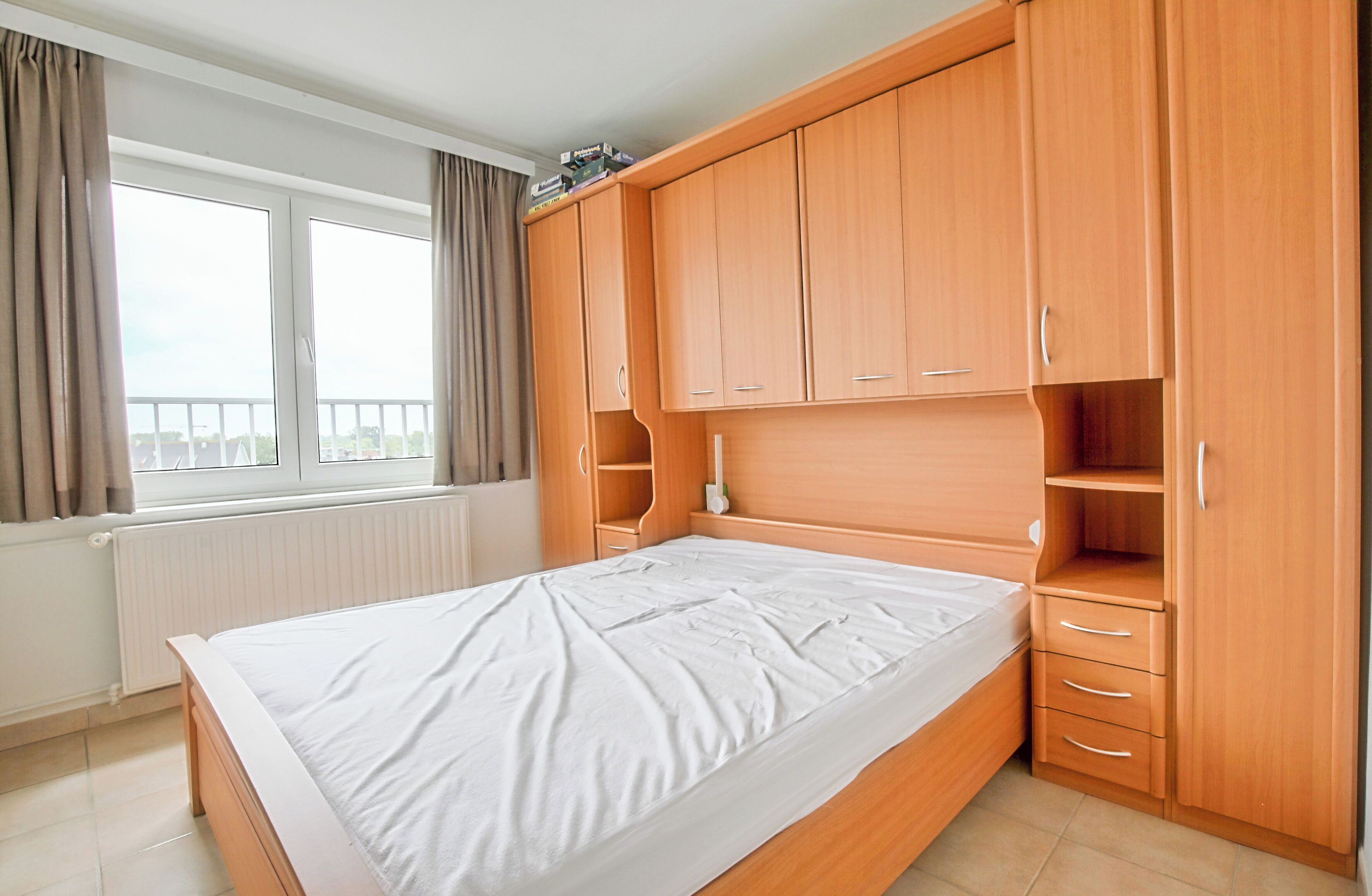 Camera da letto con un letto grande, un armadio in legno e una finestra con tende.