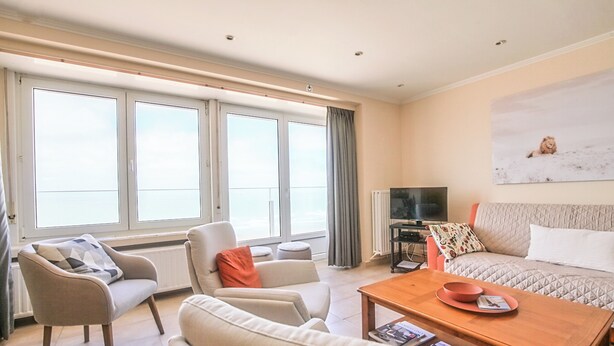 A modern living room with a sofa, armchairs, a coffee table, and a television.