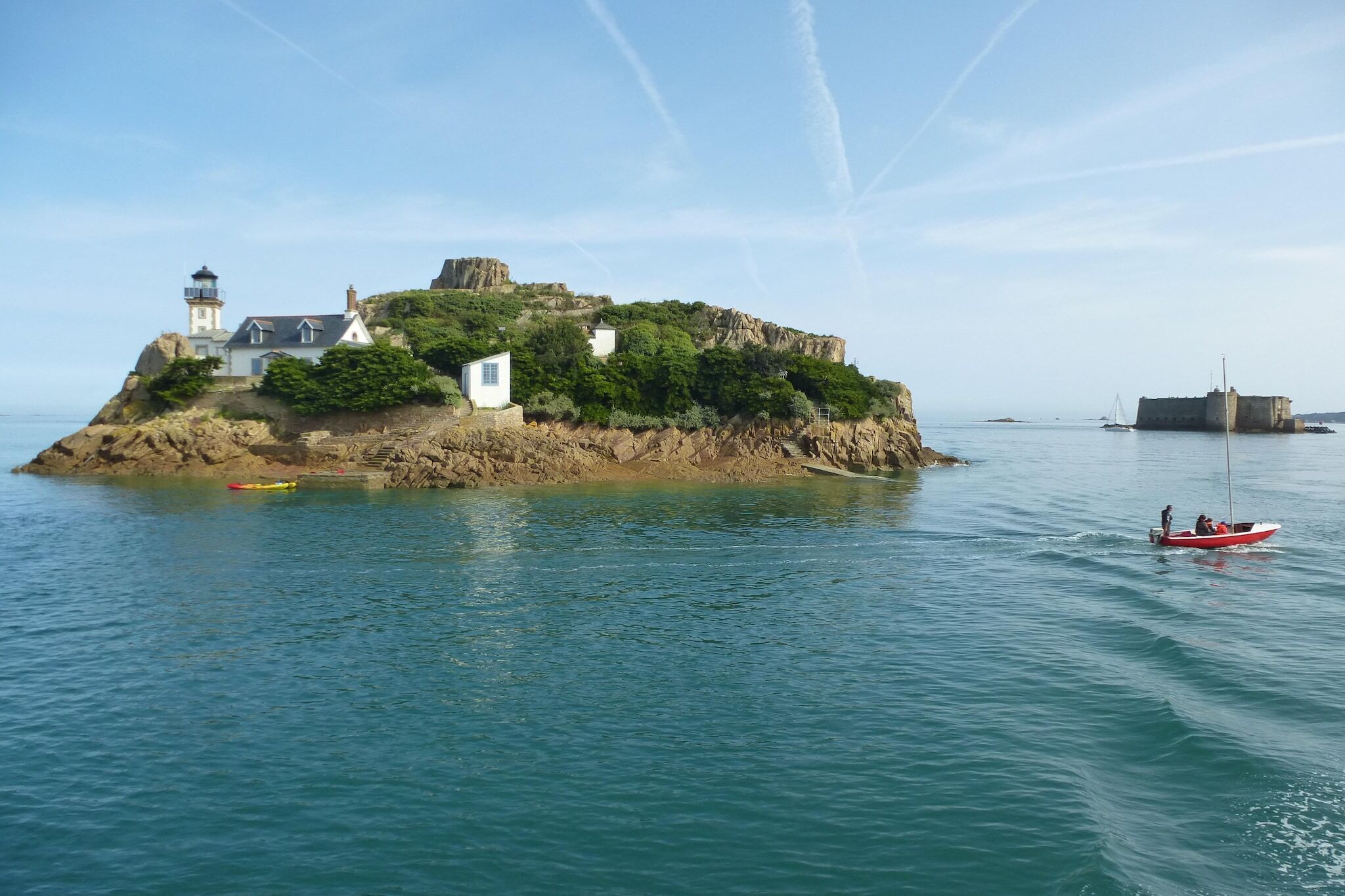 Una isla costera con un faro, una casa pequeña y una fortaleza.