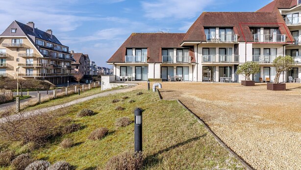 A residential building with multiple balconies, a gravel courtyard, and a clear sky. - 2 bedroom accommodation in Oostduinkerke (Oostduinkerke)