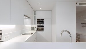 A modern kitchen with white cabinetry, a stainless steel faucet, and built-in appliances including a microwave and oven. - 2 bedroom accommodation in Oostduinkerke (Oostduinkerke)