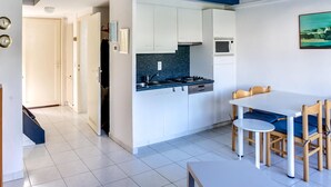 Eine moderne Küche mit weißen Schränken, einer blauen Arbeitsplatte und einem Essbereich mit weißem Tisch und Holzsesseln.