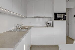 A modern kitchen with white cabinetry, a stainless steel sink, and a coffee machine. - 1 bedroom accommodation in Oostduinkerke (Oostduinkerke)