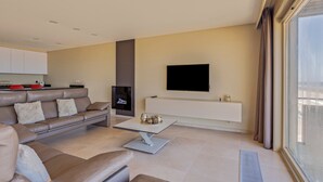 Un salon moderne avec un canapé, une table basse et un téléviseur à écran plat fixé au mur.
