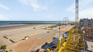 Une vue sur la plage avec une grande grue jaune, une grande roue et un bâtiment en construction.