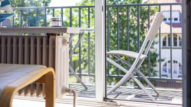 Un balcon avec une chaise, une table et un radiateur.