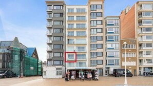 Ein mehrstöckiges Gebäude mit einem EuroBeach-Geschäft im Erdgeschoss, umgeben von weiteren Gebäuden und einer Baustelle.