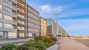 A modern apartment building with multiple balconies, a paved walkway, and a clear sky. - 2 bedroom accommodation in Sint Idesbald (Sint Idesbald)