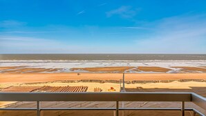 A beach view from a balcony with a clear sky, sandy beach, and a wooden deck. - 2 bedroom accommodation in Sint Idesbald (Sint Idesbald)