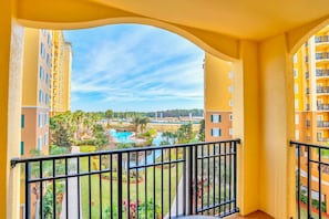 Ein Balkon mit Blick auf einen Pool und die umliegende Bepflanzung.
