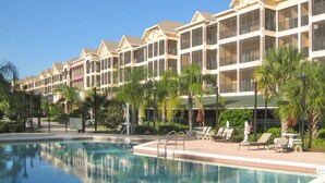 Un hôtel doté d’une piscine, de plusieurs balcons et de palmiers.