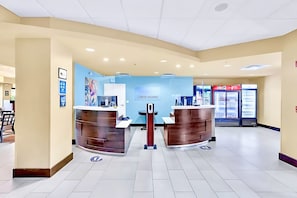 Un espace d’accueil avec deux comptoirs, un mur bleu orné d’une enseigne et un réfrigérateur Coca-Cola.