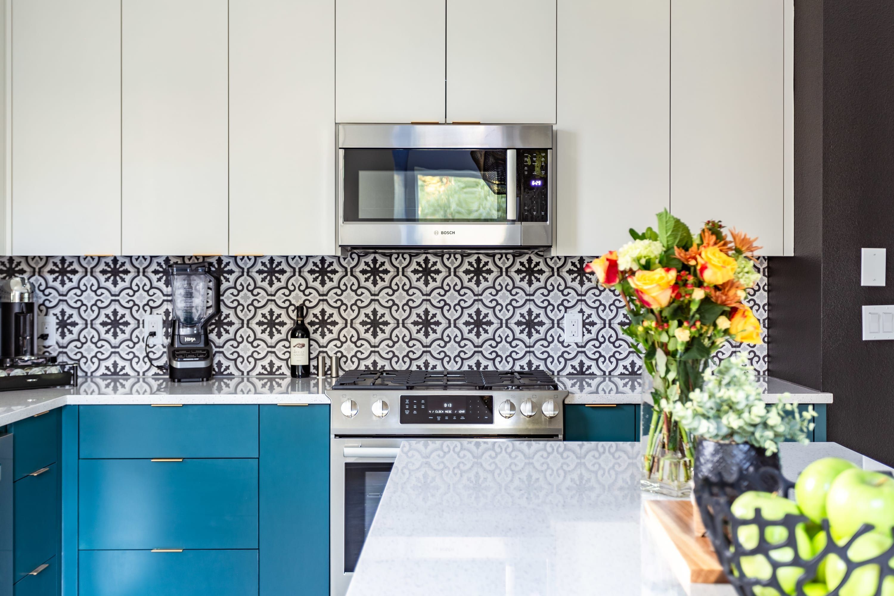 A modern kitchen with a Bosch microwave, a coffee maker, and a fruit bowl on the counter.