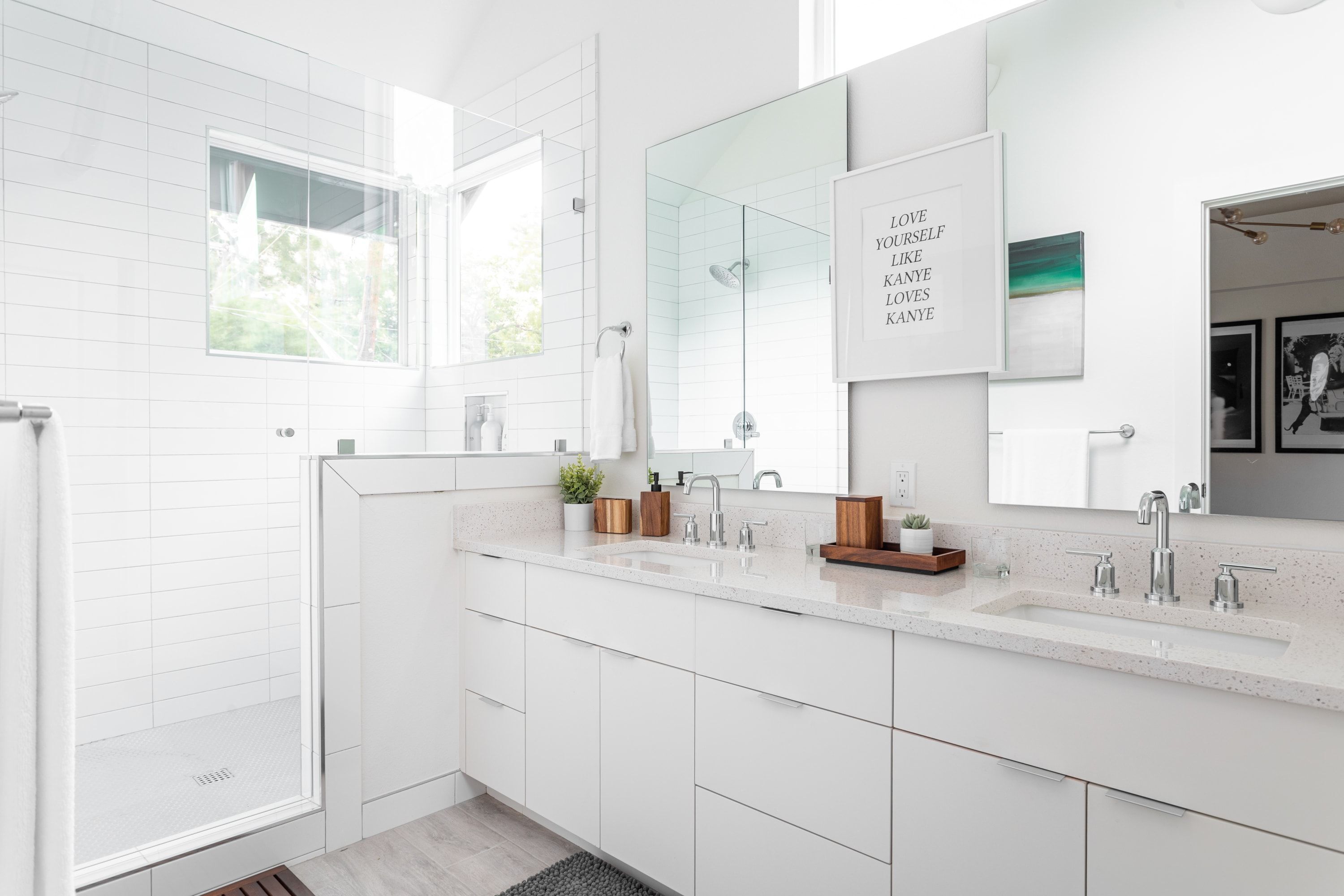 A modern bathroom with a large mirror, a shower, and a vanity with a sink.