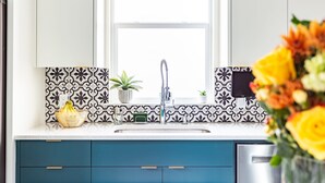 Eine Küche mit Fenster, Spüle, Topfpflanze, einer Bananenkörbchen und einer Blumenvase.