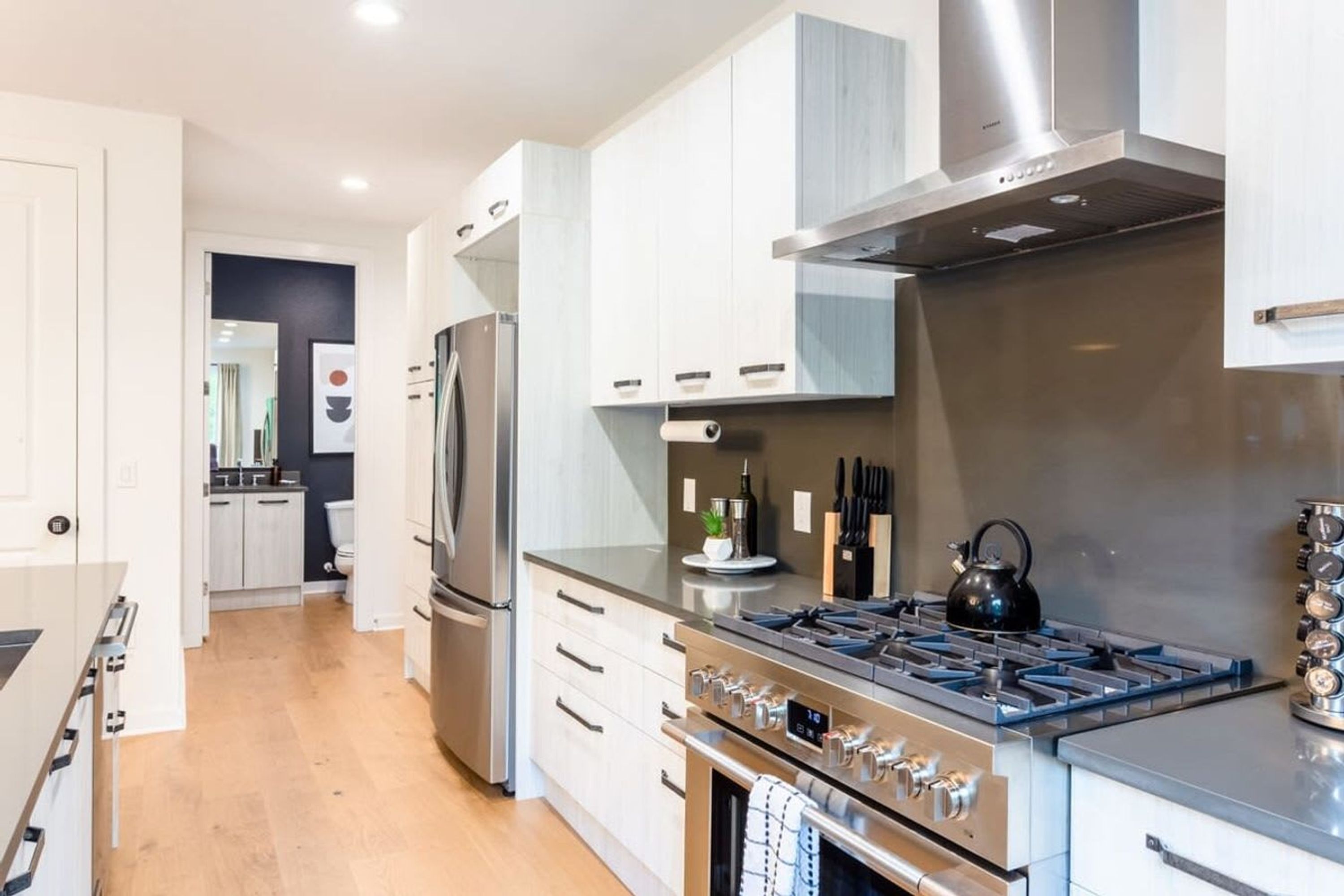 A modern kitchen with stainless steel appliances, white cabinetry, and a central island.
