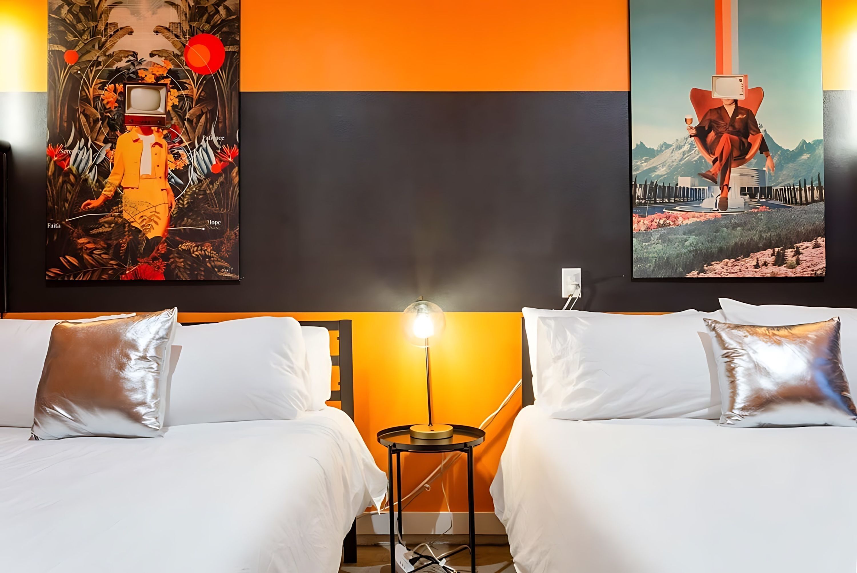 Een hotelkamer met twee bedden, een nachtkastje met een lamp, en twee grote kunstwerken aan de muur.